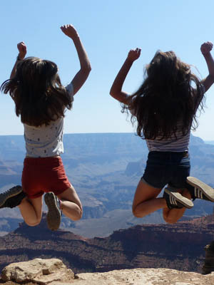 Two girls jumping in the air with the Grand Canyon in the background